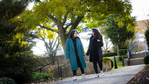 two students walking and talking outdoors on campus