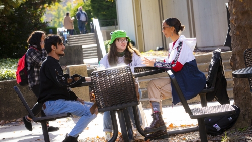 students sitting outdoors around table with laptops