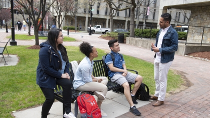 man speaking with students on bench