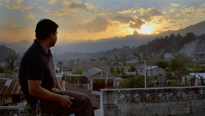 man looking over a town at dawn