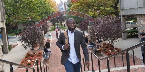 man walking up the steps with rutgers-newark arch in the background