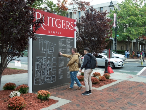 two people referencing map of rutgers-newark campus on a sign