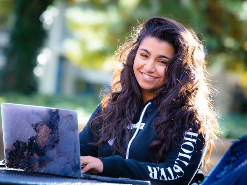 smiling female student on laptop outdoors
