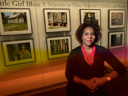woman standing in front of exhibit on nina simone's childhood home