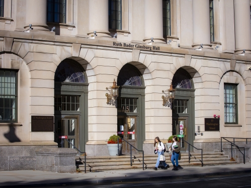 two students walking on sidewalk in front of building