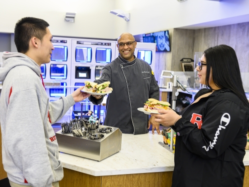 dining hall worker handing food to students