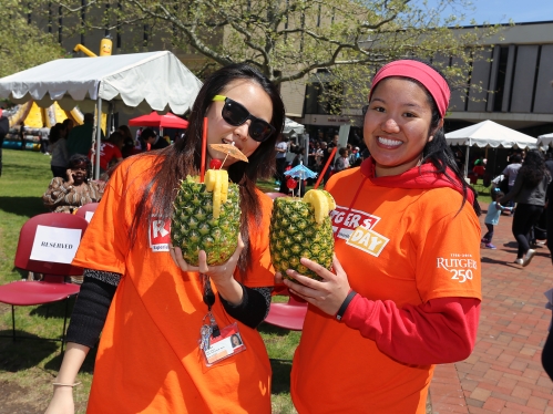 two students holding up pineapple drinks