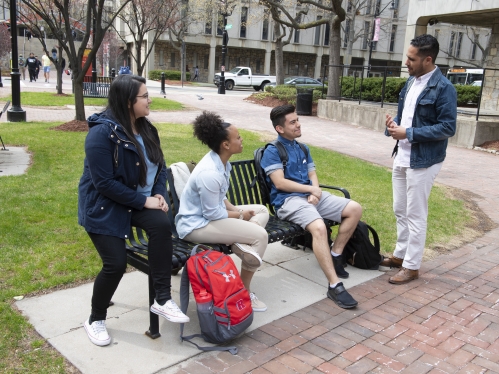 man speaking with students on bench