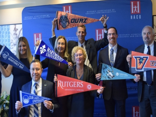 chancellor cantor holding a Rutgers-newark pennant next to other attendees of the hispanic association of colleges and universities round table